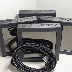 May include: Five black square-shaped devices with the text "3D ROB" printed on them. The devices have a black cable attached to them.