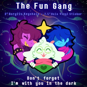 May include: A 3-inch acrylic keychain and 2.5-inch holo vinyl sticker set titled The Fun Gang. The design features three cartoon characters in a heart shape with a yellow star above, set against a dark purple background with the text Don't forget I'm with you in the dark.