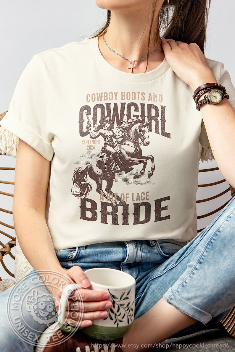 K&ouml;nnte beinhalten: Cremefarbenes T-Shirt mit brauner Grafik einer Cowgirl auf einem Pferd, Text "Cowboy Boots and Cowgirl Bride" und "September 2024". Das Shirt ist unisex.