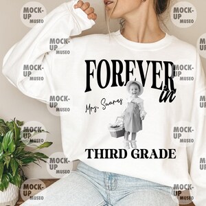 Może przedstawiać: Biała bluza z długim rękawem z czarnym napisem FOREVER in THIRD GRADE. Projekt zawiera czarno-białe zdjęcie dziecka w kapeluszu i sukience trzymającego koszyk oraz odręczny napis Mrs. Suares.