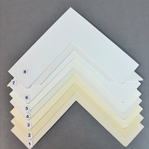 May include: Eight white mount boards, numbered 1 to 8, arranged in a pyramid shape. The mount boards are different shades of white, ranging from a very bright white to a cream colour.