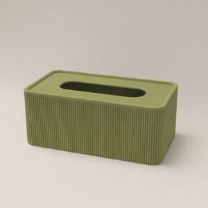 Peut inclure: Un distributeur de mouchoirs rectangulaire de couleur vert clair. La boîte présente une texture striée sur les côtés et un dessus lisse avec une ouverture ovale pour la distribution des mouchoirs. Design simple et moderne.