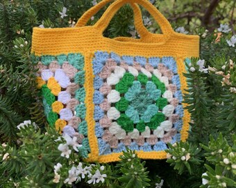 May include: A yellow crocheted tote bag with a green, blue, and white granny square pattern.