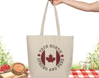 May include: A beige canvas tote bag with a red and white Canadian flag design. The bag has the text "True North Strong and Free" printed around the flag.