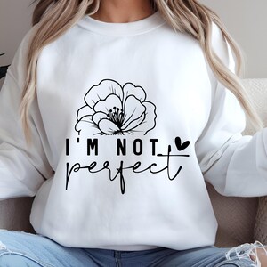 May include: White sweatshirt with a black floral design and the text "I'm not perfect" with a small heart.
