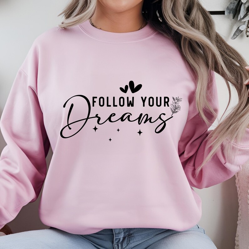 May include: Pink sweatshirt with the text "FOLLOW YOUR DREAMS" in black lettering with two small hearts and a floral design.