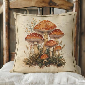May include: A throw pillow with a vintage illustration of red and white mushrooms with brown stems and green foliage. The pillow has a beige linen background with handwritten text in brown ink.