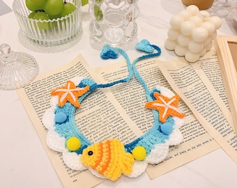 Peut inclure: Un collier pour animal de compagnie en crochet bleu et blanc avec un poisson jaune et orange, deux étoiles de mer et des pompons jaunes et bleus.