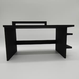 May include: Black wooden desk organizer with two shelves and a top shelf. The organizer is made of wood and has a simple design.
