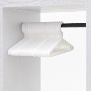 Puede incluir: Un conjunto de perchas de plástico blanco ordenadas en una barra negra dentro de un armario blanco. Las perchas son todas del mismo tamaño y forma, creando un aspecto limpio y organizado. El armario es blanco con un patrón texturizado.