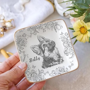 May include: Square ceramic trinket dish with a gold rim, featuring a black and white illustration of a German Shepherd dog named "Bobby." The dish is decorated with floral and butterfly designs.