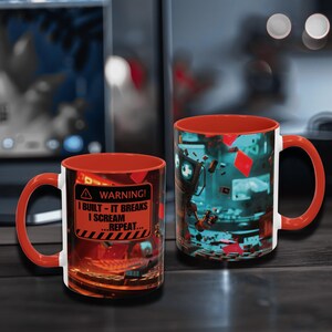 Peut inclure: Deux mugs en céramique avec intérieurs et anses rouges. L'un des mugs présente un panneau d'avertissement avec le texte "I BUILT - IT BREAKS I SCREAM ...REPEAT...". L'autre mug a un design futuriste avec un code couleur turquoise et rouge.