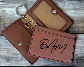 May include: Brown leather key chain with a small card holder. The card holder has the initials "BAM" engraved on it.