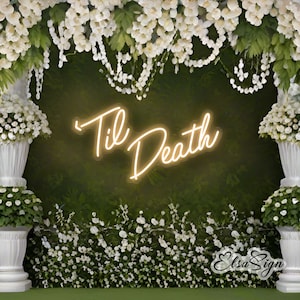 May include: A white neon sign with the text "Til Death" in a cursive font. The sign is hanging in front of a green wall decorated with white flowers.