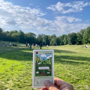 May include: A green and white card with a cartoon illustration of a park with a tower in the background. The card has the title "Hasenheide" and the text "MAMAAN DEJ! Dann gehen wir jetzt mal in den SCHLOSS STEIGERN!" and "und second floor und die gehen!" The card also has a scale with the text "100g Gras mit 100E", "200g Gras mit 200E", "500g Gras mit 500E", and "1000g Gras mit 1000E".