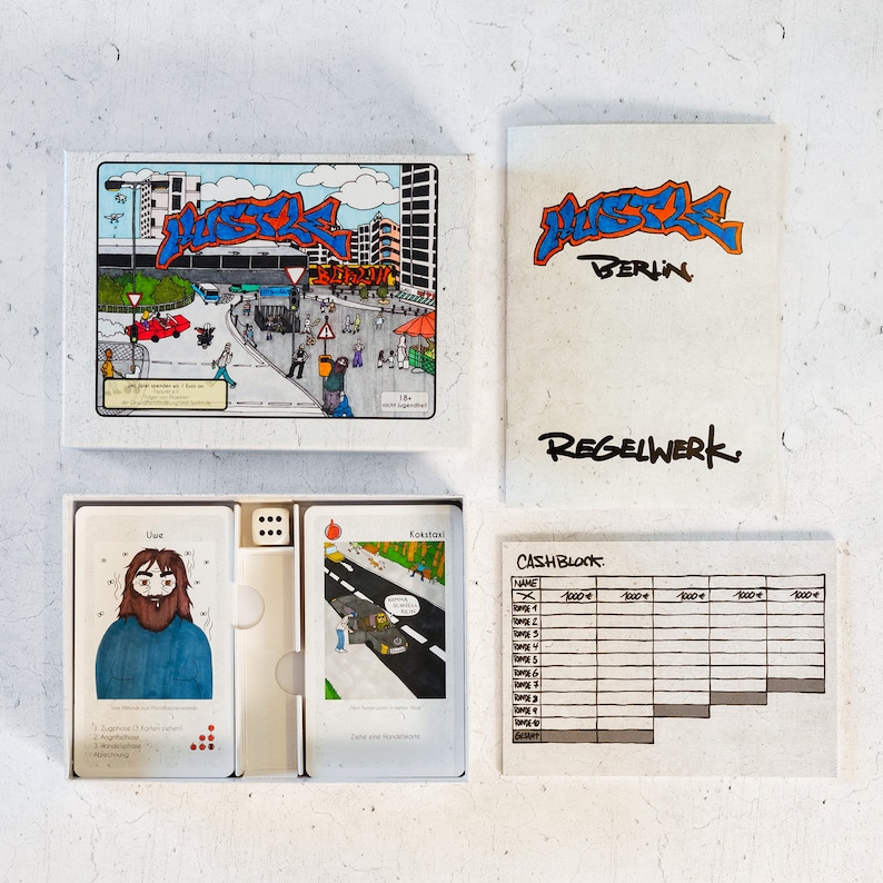 May include: A board game called "Hustle Berlin" with a colorful illustration of a city street scene on the box lid. The game includes a cash block, dice, and cards with illustrations of people and places.