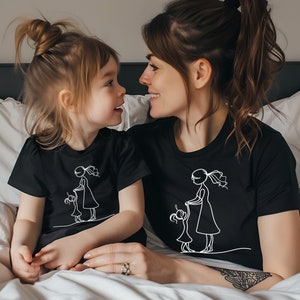 ミニミーママTシャツ、ダンシングデュオ母と子、ブラックTシャツ、母と娘の愛、ラインアートデザイントレンド、シャツママとミー