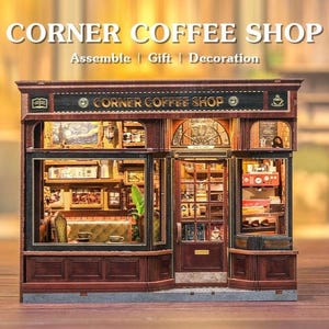 May include: A miniature Corner Coffee Shop model with detailed wooden construction. The model features a storefront with windows, a door, and interior elements like a coffee machine and framed artwork. The text "CORNER COFFEE SHOP" is displayed at the top.