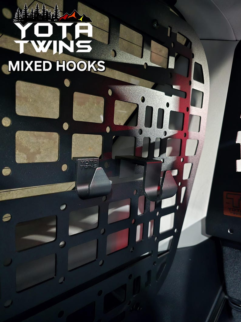 May include: Black metal cargo rack with a grid pattern and two hooks. The rack is labeled "YOTA TWINS MIXED HOOKS".