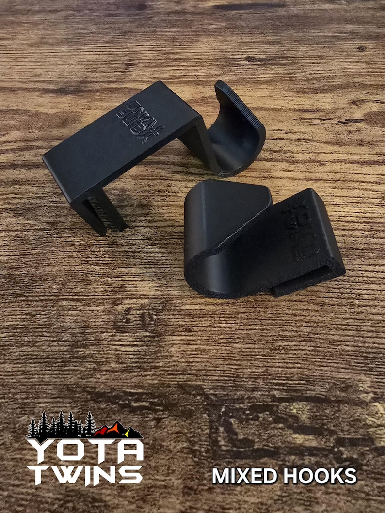 May include: Two black plastic hooks with the text "YOTA TWINS" printed on them. The hooks are on a wooden surface. The text "MIXED HOOKS" is printed below the hooks.