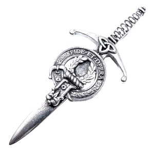 May include: A silver-toned kilt pin featuring a sword with a Celtic knot design and a circular crest with the text "Fide Et Opera".