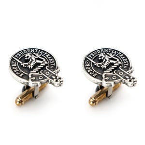 May include: A pair of silver cufflinks with a black enamel design featuring a lion and the text "Prudentia Praesta" and "Fortis In Bore."
