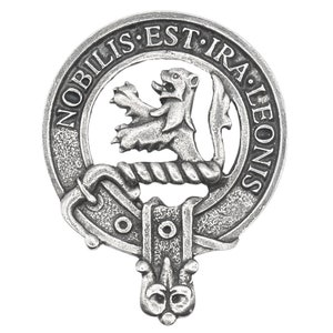 May include: A silver-toned clan crest badge with a detailed design. The badge features a lion rampant within a circular frame, with the inscription "NOBILIS EST IRA LEONIS". The design includes intricate scrollwork and a decorative bottom element.