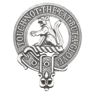 May include: A silver-toned metal clan crest featuring a stylised cat sitting on a rope. The crest is surrounded by a circular band with the text "TOUCH NOT THE CAT BUT A GLOVE".