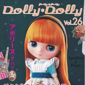 Puede incluir: Una portada de revista con una muñeca de pelo naranja que lleva un vestido azul y blanco. La revista se titula "Dolly*Dolly" y el texto de la portada dice "Apolline a Paris" y "Muñecas de tela hechas a mano".