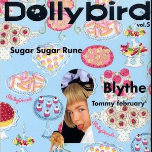 May include: A magazine cover with a blue background and a keyhole in the center. The magazine is titled "Dollybird" and features a girl with blonde hair and a blue bow. The magazine cover also features the text "Sugar Sugar Rune" and "Blythe Tommy february".