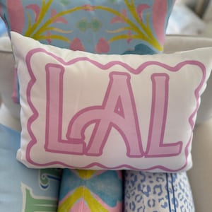 May include: A white pillow with a pink scalloped border and the word "LAL" in large pink letters.