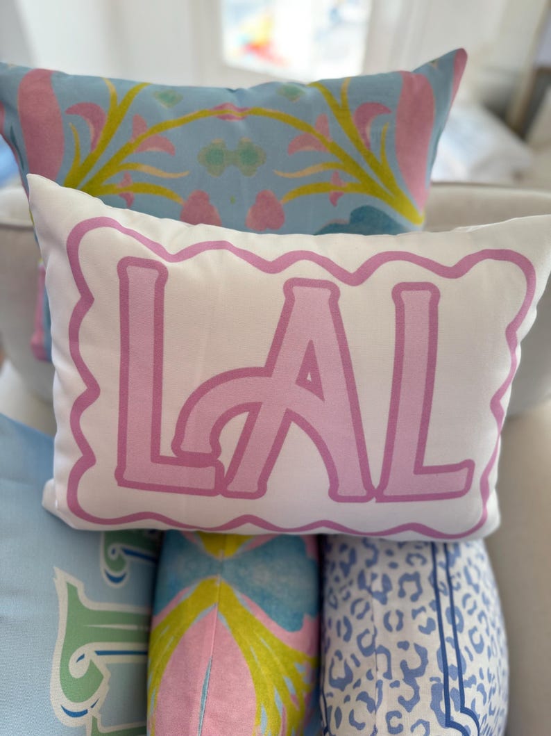 May include: A white pillow with a pink scalloped border and the word "LAL" in large pink letters.