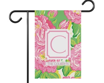 Peut inclure: Un drapeau de jardin floral avec des fleurs roses et des feuilles vertes. Le drapeau présente un cadre blanc avec la lettre "C" et le texte "THE COLBERTS". Il est monté sur un support en métal noir.