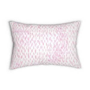 May include: A rectangular throw pillow featuring a white background with a repeating pattern of small, vertical, light pink dashed lines distributed across the entire surface of the fabric, creating a consistent and uniform textured appearance.