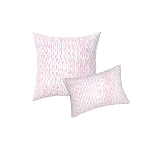 May include: A square throw pillow and a rectangular throw pillow, both featuring a white base colour with a repeating pattern of small, vertical, light pink dash marks distributed across the entire surface of the fabric covers.