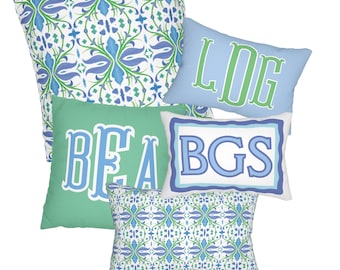 May include: A collection of decorative throw pillows in various shapes and sizes. Pillows feature floral patterns in blue and green, and monogrammed initials in blue and green on a light blue and green background. The pillows are arranged on a white background.