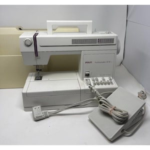 以下が含まれることがあります： 白のPfaff Hobbymatic 919-1ミシン。ハンドル、フットペダル、電源コード付き。ミシンはベージュ色のケースと様々なステッチ選択オプションを備えています。縫製プロジェクト向けに設計されています。