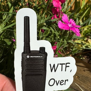 May include: A white sticker with a black Motorola two-way radio and the text "WTF, Over" in black.