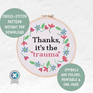 Peut inclure: Un motif de point de croix dans un cercle en bois avec l'inscription "Thanks, it's the trauma" entourée d'une couronne florale de fleurs roses et bleues. Le design comprend le texte "CROSS-STITCH PATTERN INSTANT PDF DOWNLOAD".