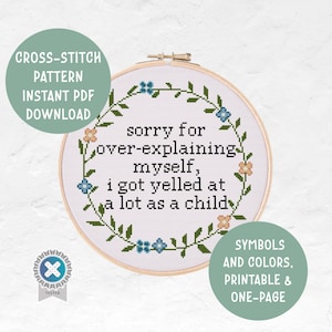 May include: A cross-stitch pattern in a wooden hoop features the text "sorry for over-explaining myself, I got yelled at a lot as a child" surrounded by a floral wreath. The design includes blue and peach flowers and green leaves.
