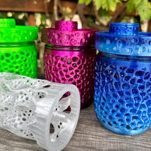 May include: Four 3D printed jars with different colored lids and textured surfaces. The jars are green, pink, blue, and clear.