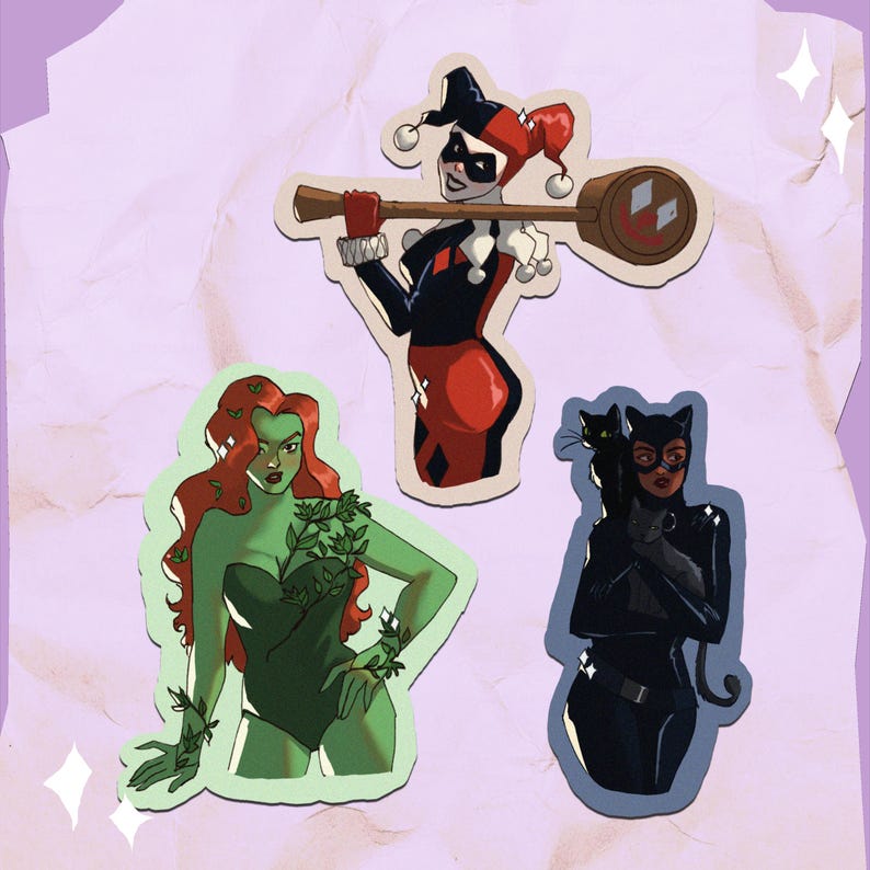 Op de afbeelding: Drie gestanste stickers met DC Comics-personages: Harley Quinn met een moker, Poison Ivy met groene huid en rood haar, en Catwoman met een zwarte kat. De stickers hebben een witte rand op een lichtpaarse achtergrond.