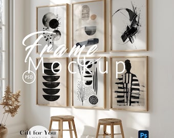 May include: A wall display featuring six framed art prints with abstract black and white designs. The frames are light wood. The text "Frame Mockup" is overlaid on the image. Two small wooden stools are in front of the wall.