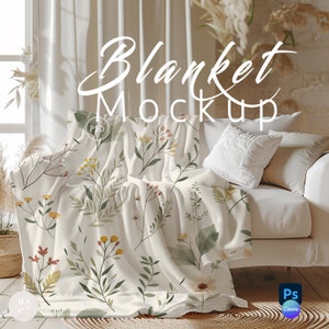 May include: A white throw blanket with a floral pattern featuring green leaves, yellow and red flowers, and a watercolor effect. The blanket is draped over a white couch with a white pillow. The text "Blanket Mockup" is written in white on a brown wall.