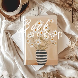May include: A white book mockup with a beige background featuring a vase with white daisies. The vase is black and white striped. The text "Book Mockup" is written in white on the book.