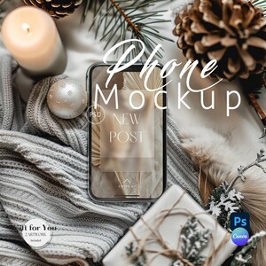 May include: A phone mockup with a white background and a blurred image of a palm leaf on the screen. The phone is surrounded by a grey knitted blanket, a silver bauble, a pine cone, and a candle. The text "Phone Mockup" and "New Post" is visible on the image.