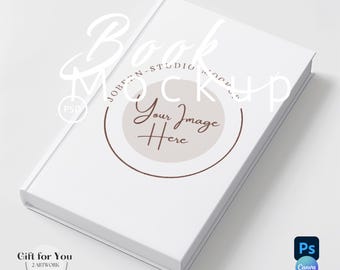 May include: White book mockup with the text "Book Mockup" and "Your Image Here" in brown text. The book is lying on a white surface.