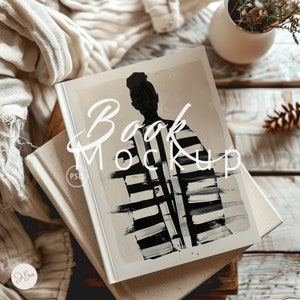 May include: A book mockup with a cover featuring a black and white abstract design of a person. The text "Book Mockup" is overlaid on the cover. The book rests on top of another book and a beige fabric.