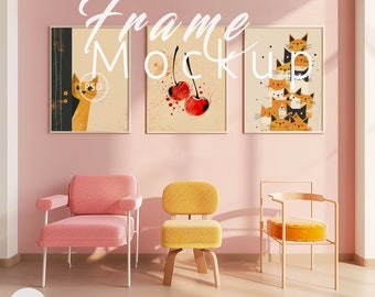 May include: Three framed illustrations on a pink wall with a pink armchair, a yellow armchair, and a gold metal chair. The illustrations are of a cat peeking around a corner, two red cherries with red splatters, and a stack of cats.