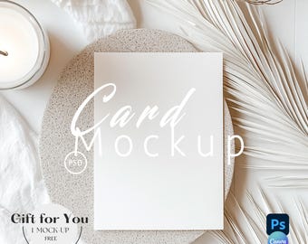 May include: A blank white card mockup with the text "Card Mockup" in a soft, elegant font. The card rests on a speckled, round, gray stone plate, with a white candle and dried palm leaves. The words "Gift for You" are also visible.